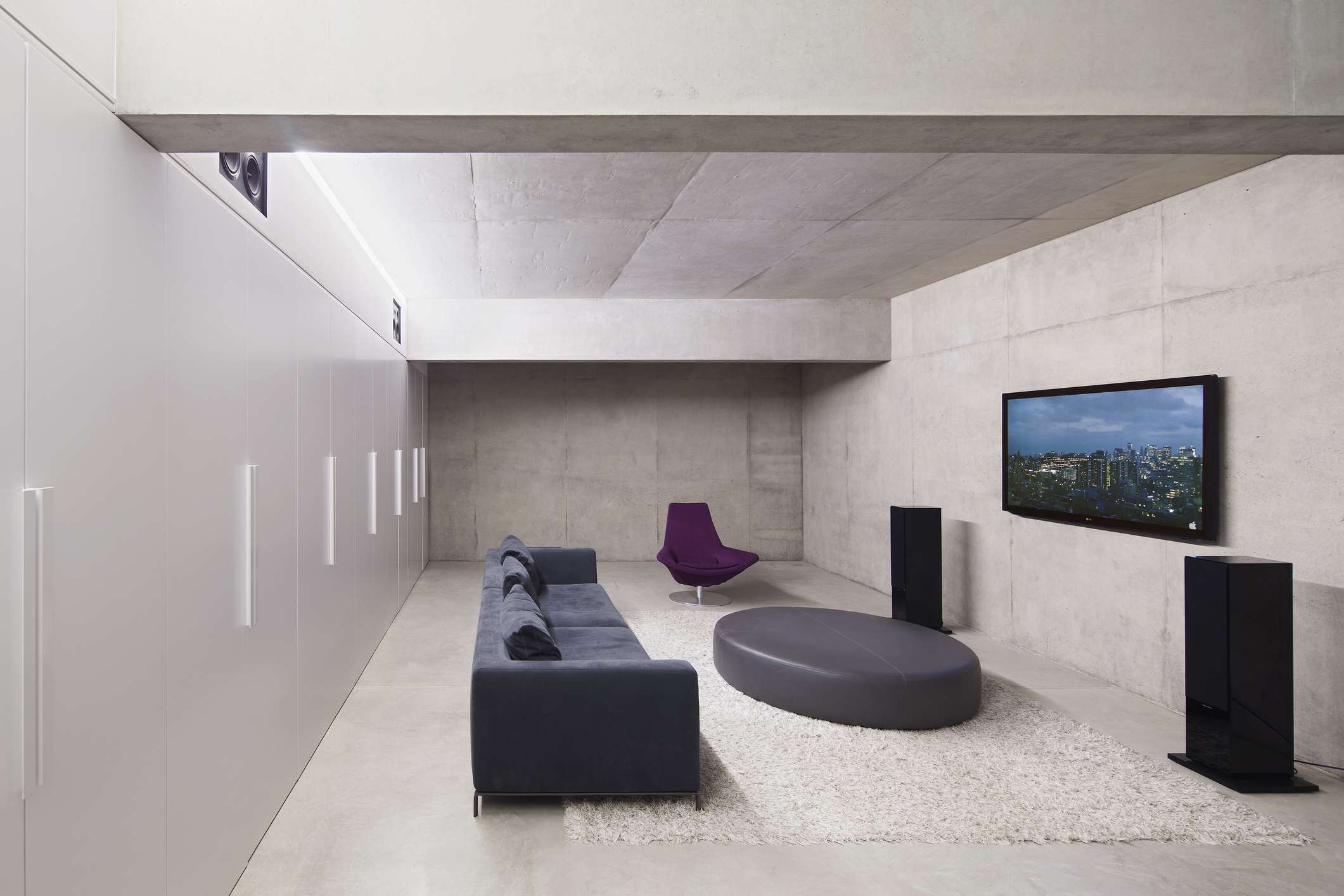 Moderní obývací pokoj s TV na stěně, stereofonními reproduktory a pohovkou