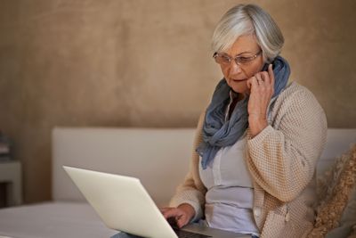 Osoba na mobilním telefonu a notebooku