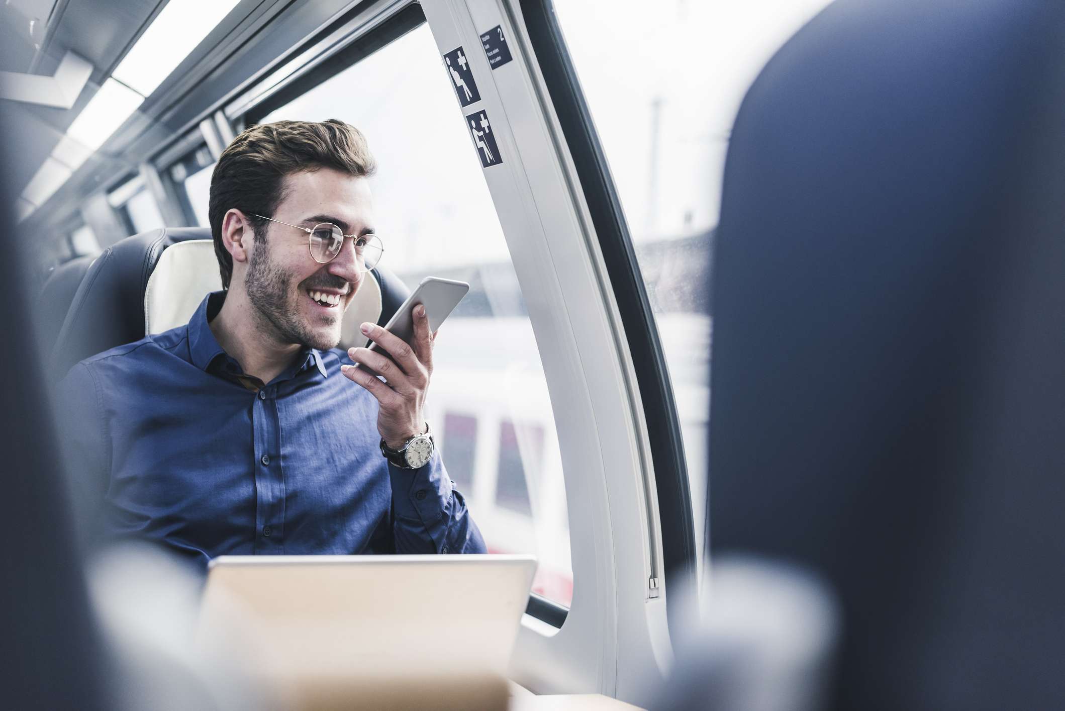 Šťastný podnikatel ve vlaku mluví do svého smartphonu