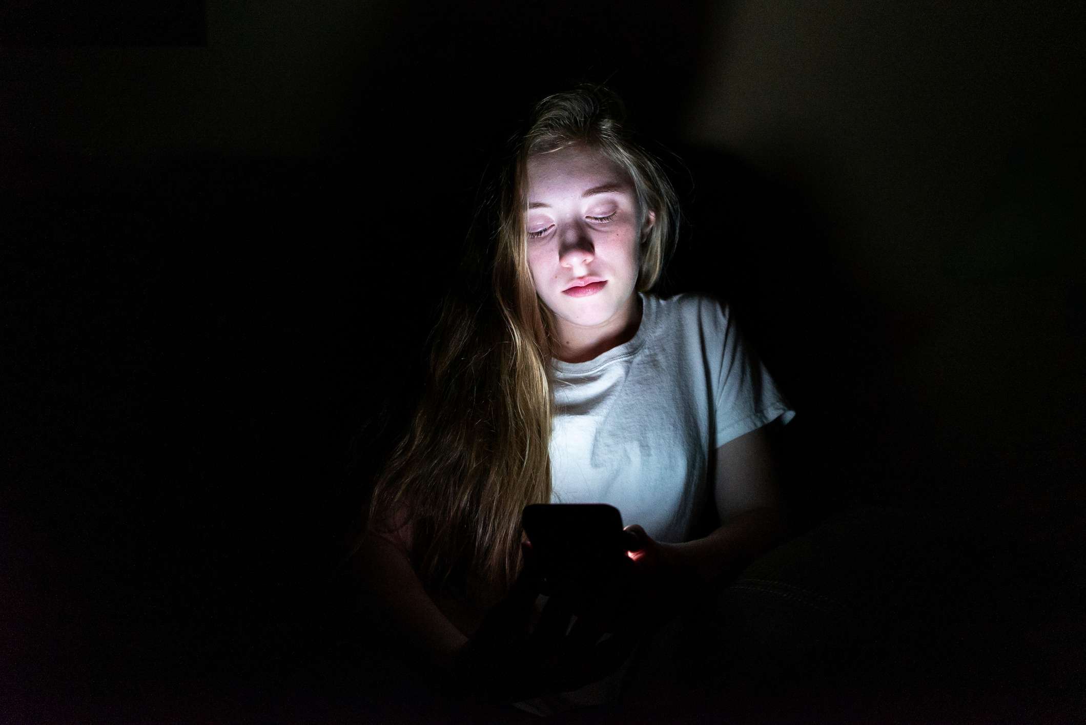 Teenager pomocí smartphone ve tmě. 