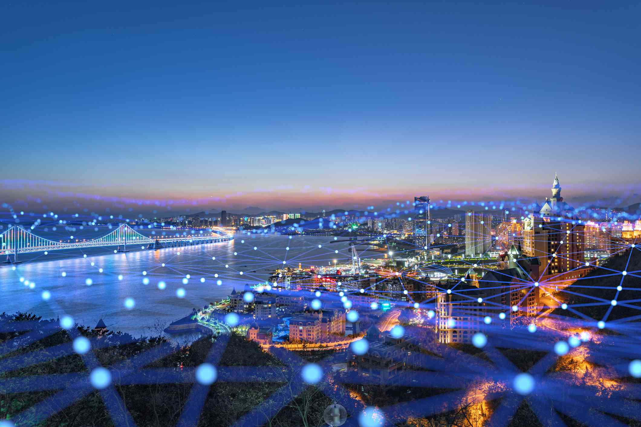 Město pokryté pavučinou transparentních modrých světel a čar představujících konektivitu