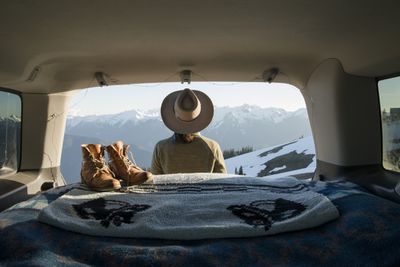 Tramp sedí v autě před zasněženými horami