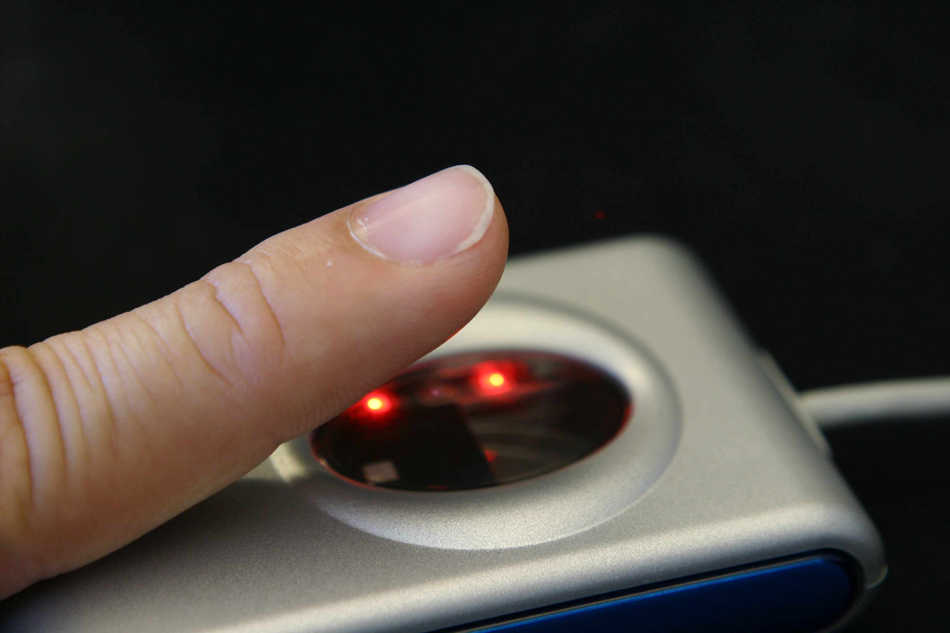 Detailní záběr na prst na skeneru otisků prstů.