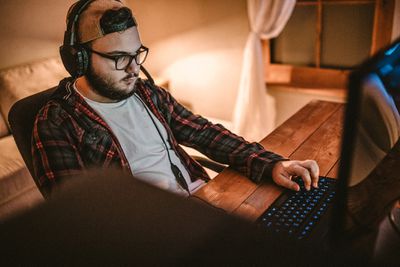 Vousatý muž hraje videohry na počítači doma