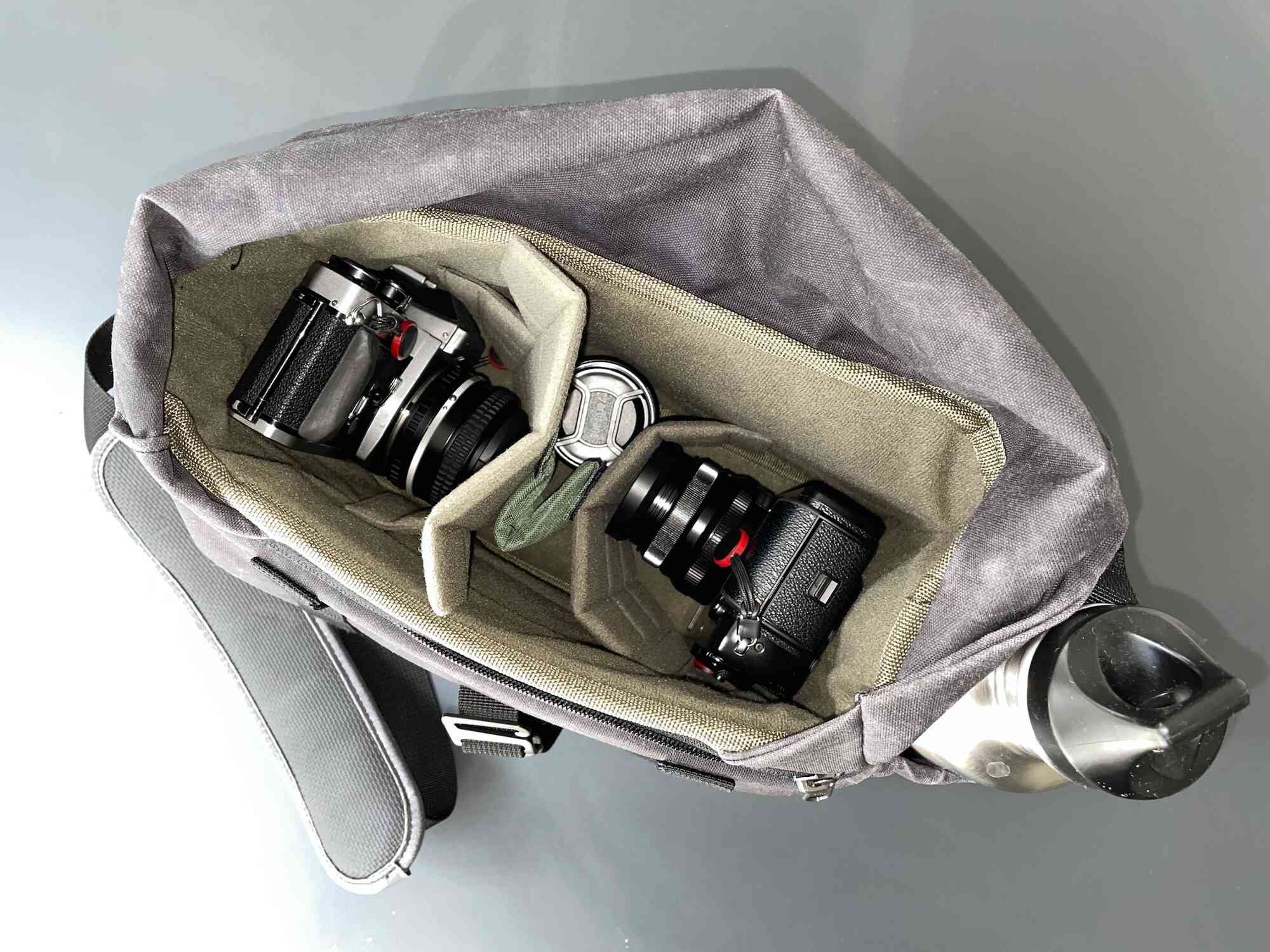 Otevřená taška na fotoaparát Wotancraft, která zobrazuje dvě kamery a objektiv ve vnitřním úložném prostoru. 