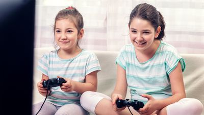Dvě mladé dívky hrající zábavné videohry na konzoli PlayStation.