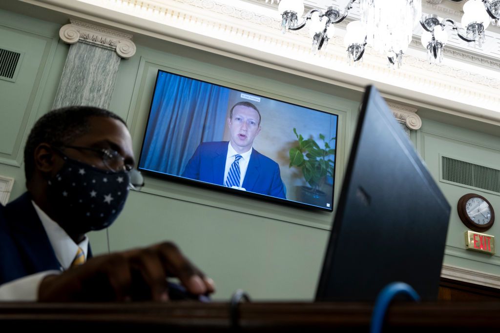 Mark Zuckerberg se objeví v televizi za osobou u stolu v masce
