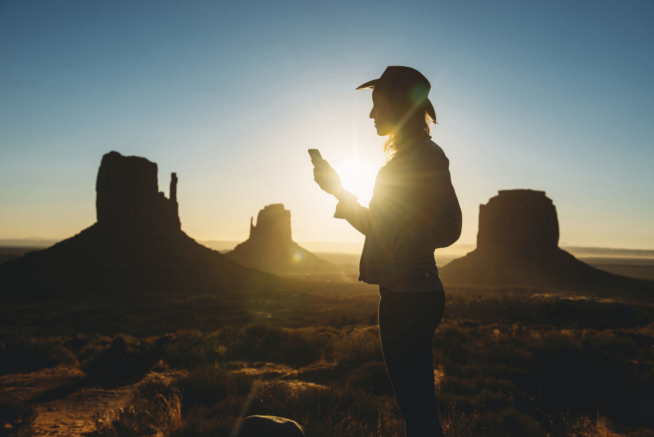 Někdo používá smartphone za úsvitu v Monument Valley v Utahu. 
