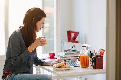 Domácí nezávislý pracovník pomocí notebooku při snídani
