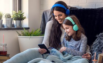 Žena a její dcera nosit sluchátka a poslouchat hudbu na Apple iPhone.