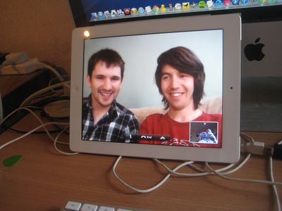 Obrazovka počítače zobrazující 2 muže a menší obrazovka s někým, kdo drží telefon.