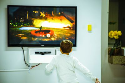 Chlapec hraje videohry před TV s plochou obrazovkou