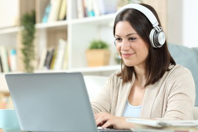 Osoba se sluchátky na uších a laptopem upravující kanál YouTube