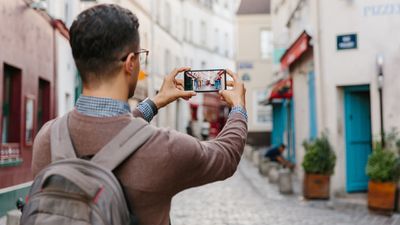 Muž na sobě batoh a fotografování se svým smartphonem při cestování do zahraničí.