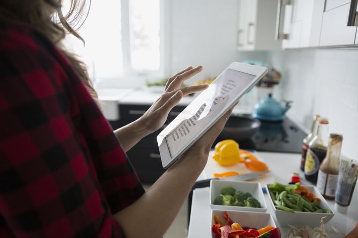 Žena s digitálním tabletu vaření v kuchyni