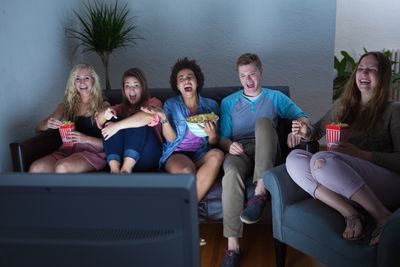 Skupina přátel, kteří sledují televizi.