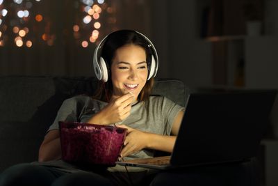 Žena s sluchátka přes ucho sledování filmu na notebooku