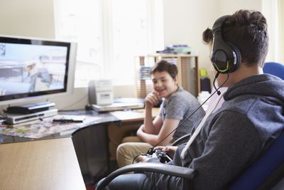 Dva chlapci sedí u počítače, hraní her online