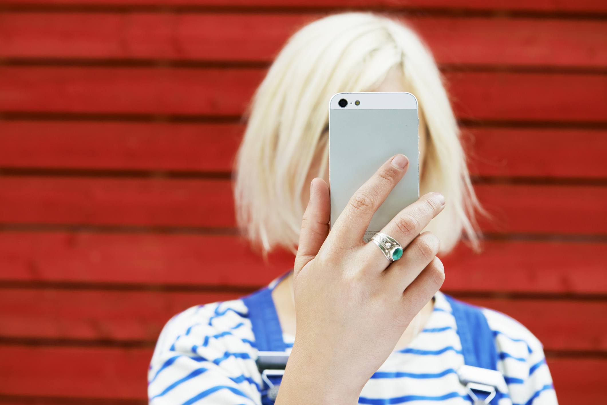 Žena drží mobilní telefon až k obličeji