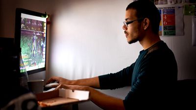 Muž nosí brýle hraní videoher na svém Pc v temné místnosti