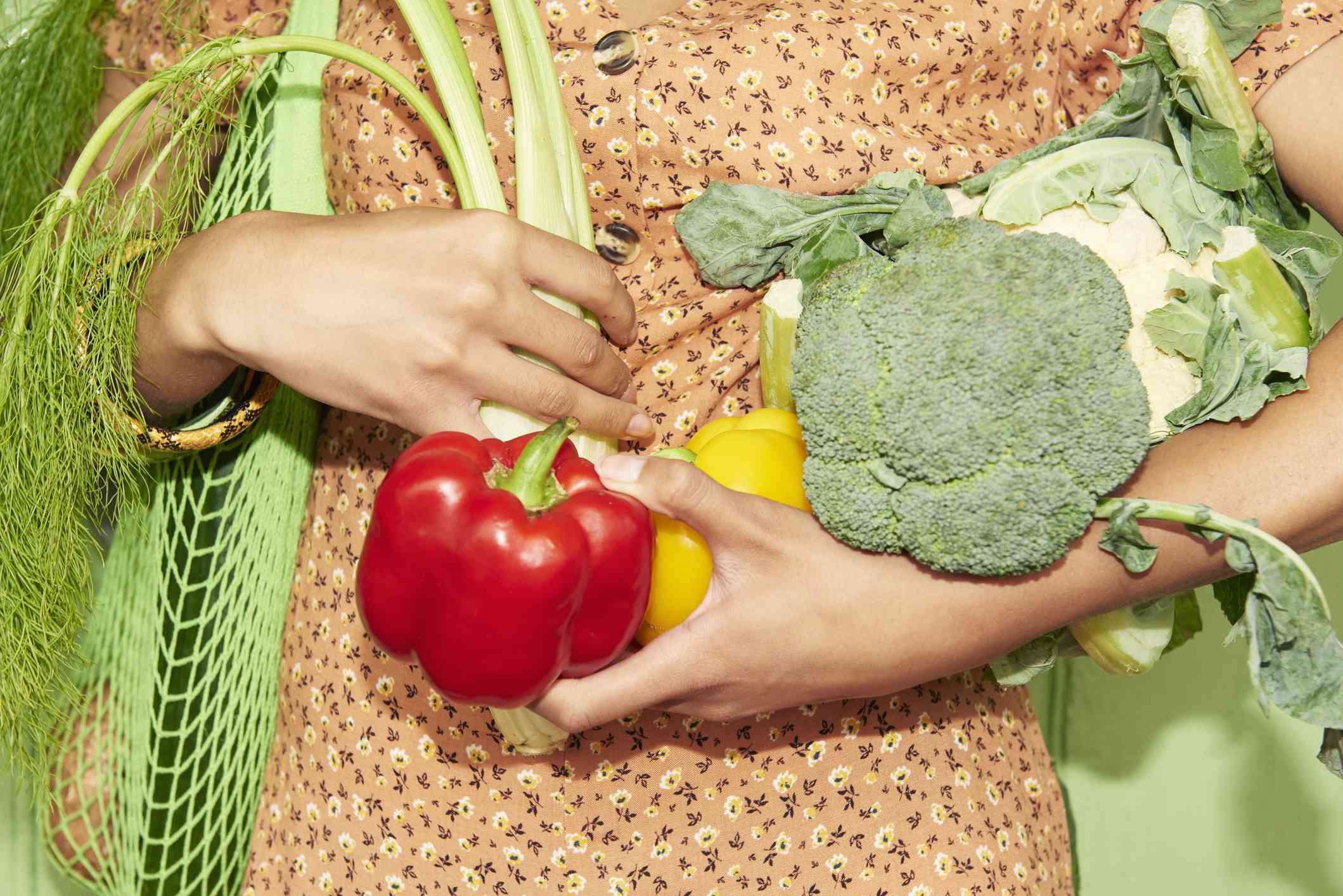 Detailní záběr na někoho, kdo drží v náručí čerstvé zeleniny.