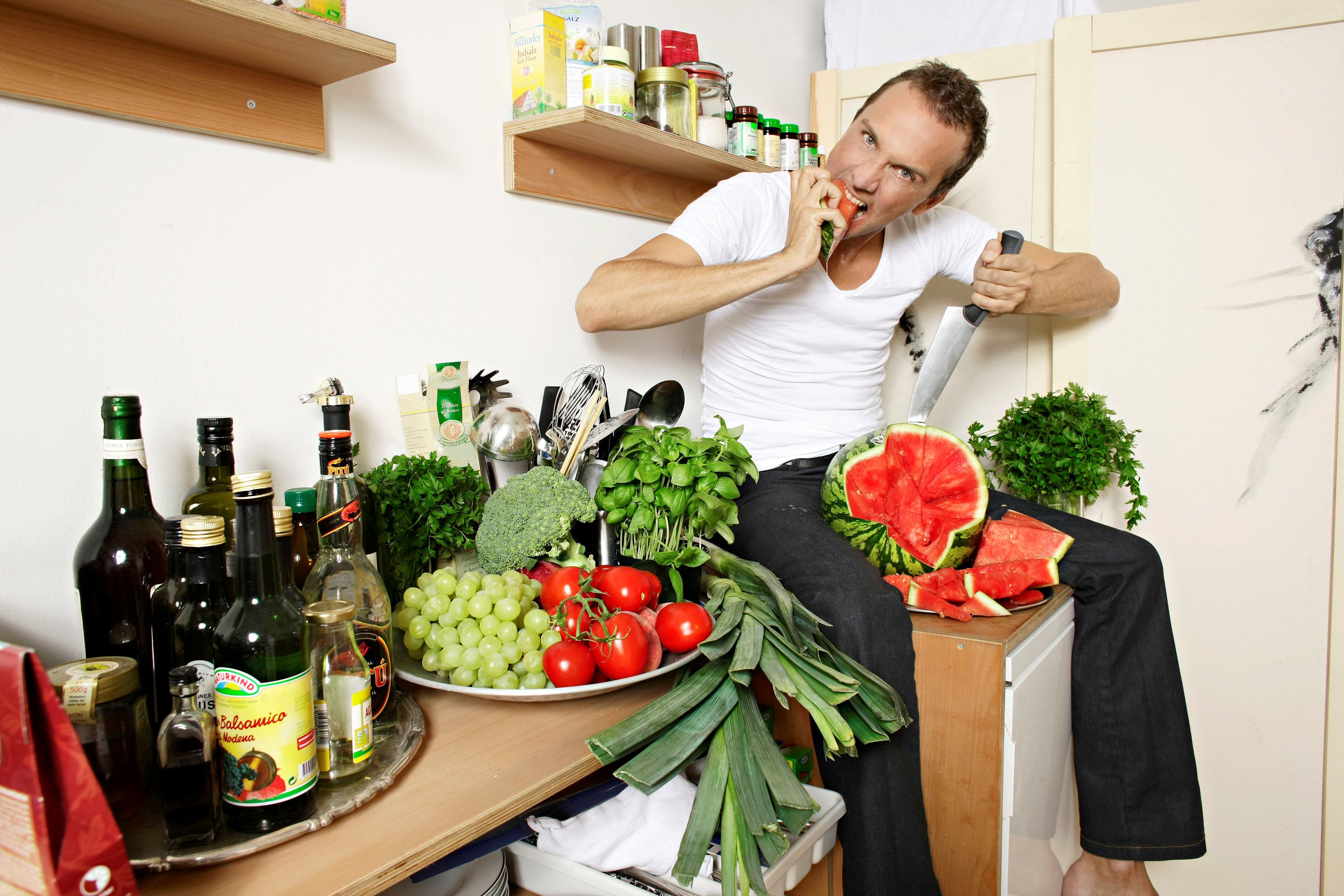 Muž sedí na kuchyňské lince s produkty a potravinami
