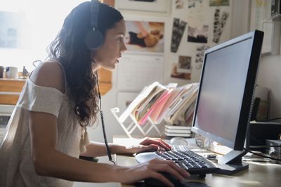 Žena u počítače se sluchátky na uších, když přesouvá hudbu do Windows Media Player.