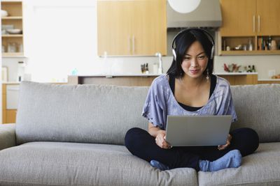 Asijské ženy na gauči s notebookem chatování přes VoIP