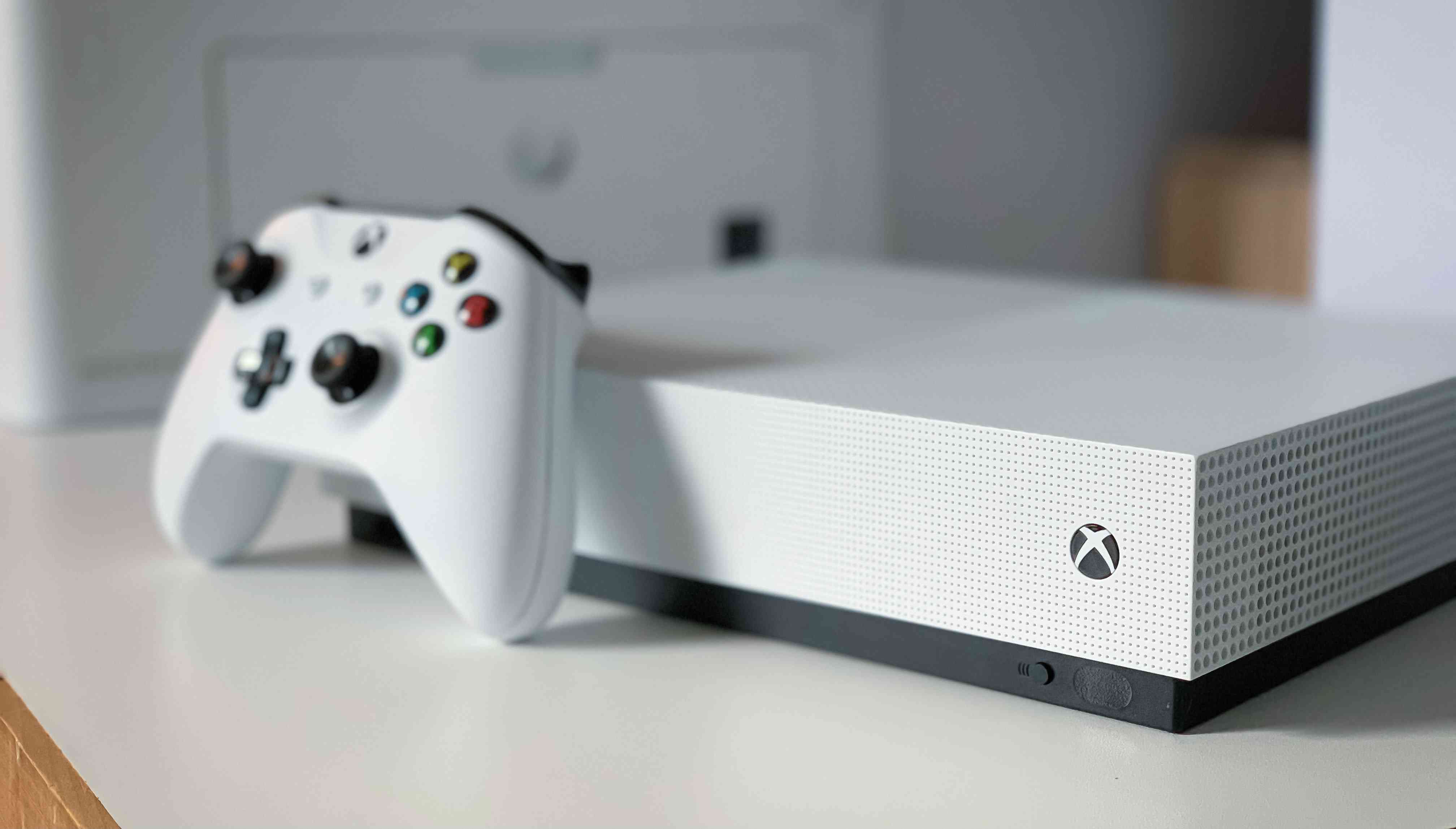 Opřela se o ni bílá konzola Xbox One s bílým ovladačem.