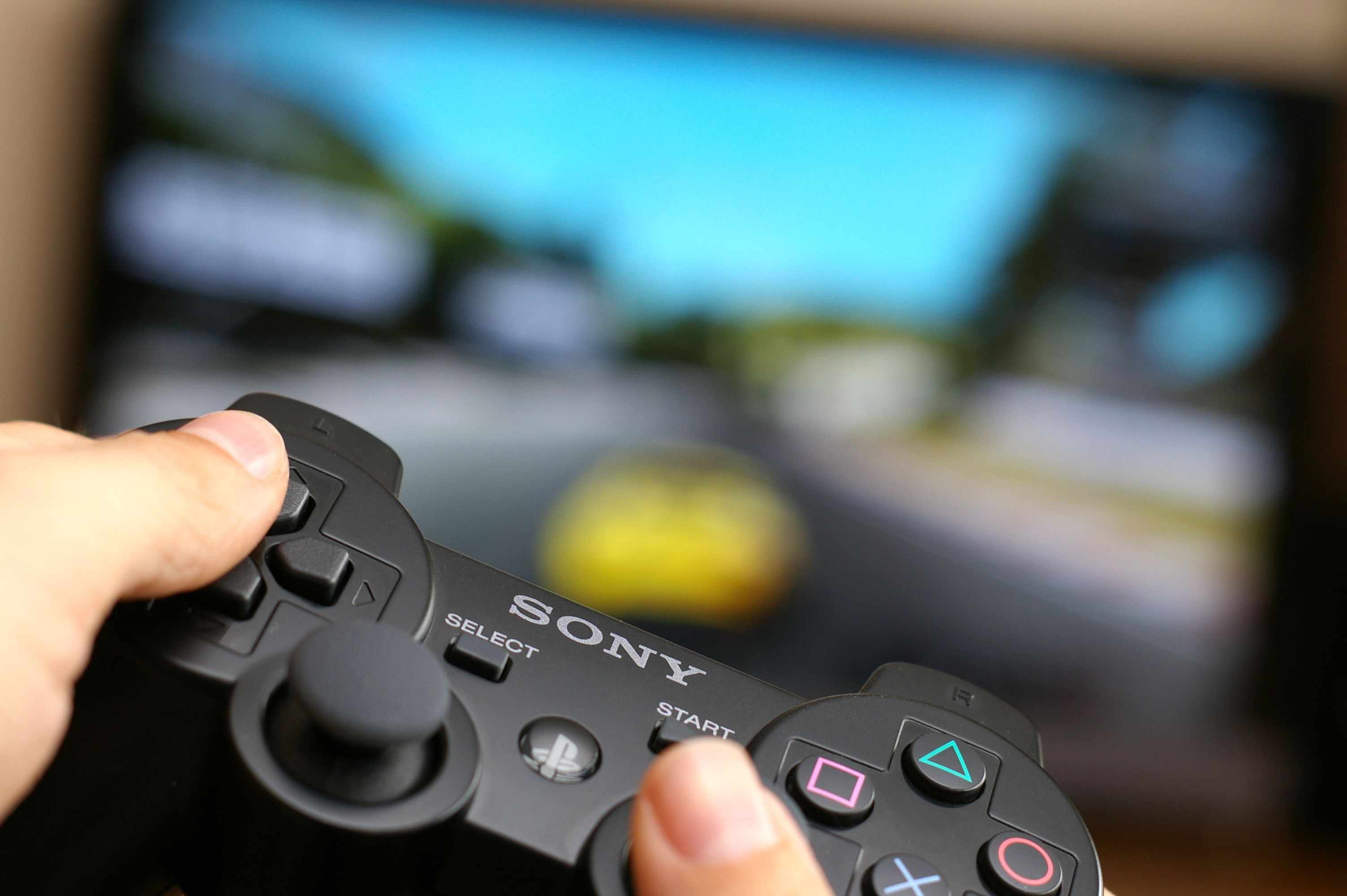 Muž, který držel bezdrátový ovladač Sony Dualshock při hraní hry Gran Turismo 5 na Playstation 3.