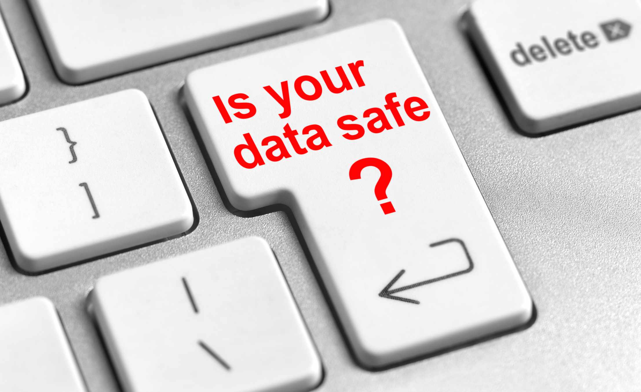 Klíč na klávesnici s vyraženým nápisem „Je vaše data v bezpečí“ červeným písmem.