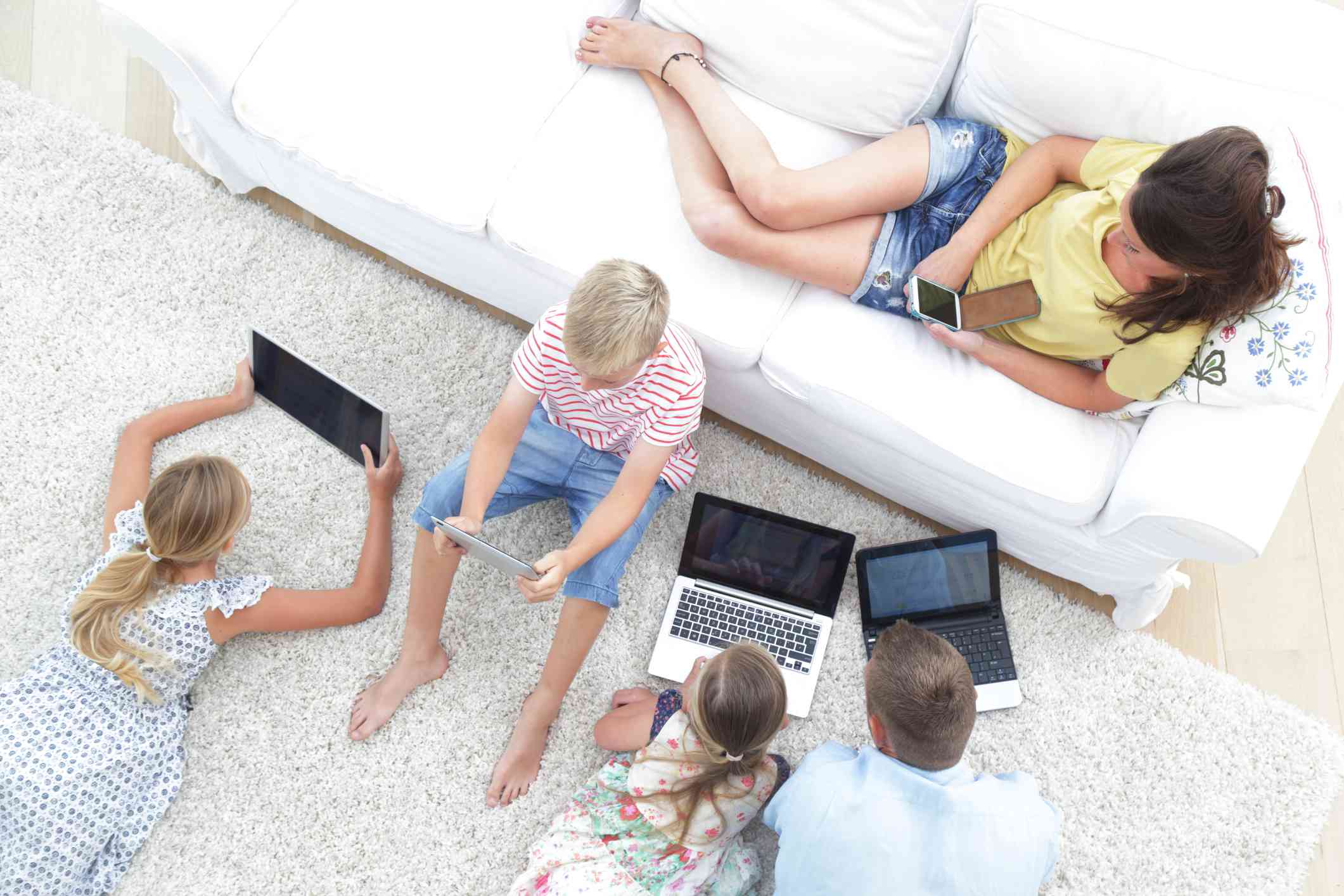 Pětičlenná rodina využívající v obývacím pokoji technologická zařízení. 