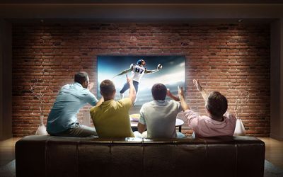 Čtyři muži sledují fotbalový zápas