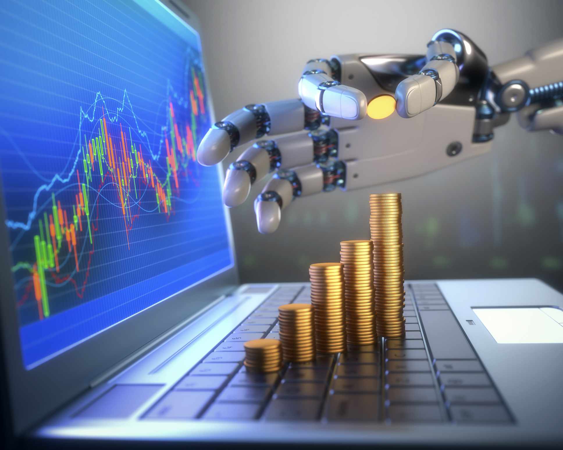 Robot ručně hromadí mince na klávesnici notebooku, který má ceny akcií zobrazené na obrazovce. 