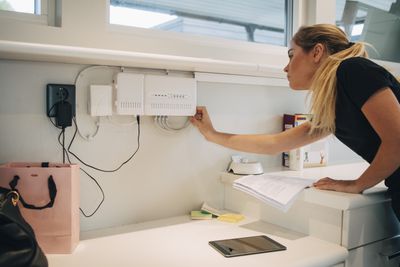 Správce sítě upravující kabel zařízení namontovaného na zdi