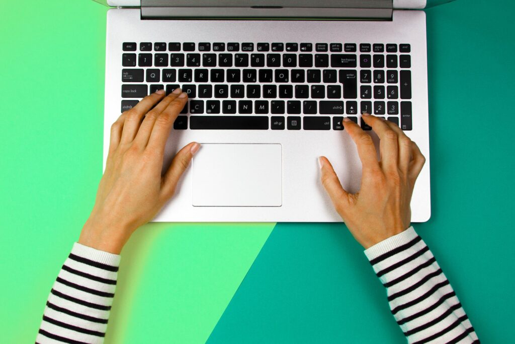 cropped hands of woman using laptop over colored background 1053740888 5be1cdc846e0fb002636ad37