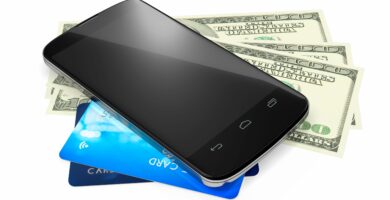high angle view of mobile phone on us paper currency and credit cards over white background 688945493 5a243922482c520037dacd8d