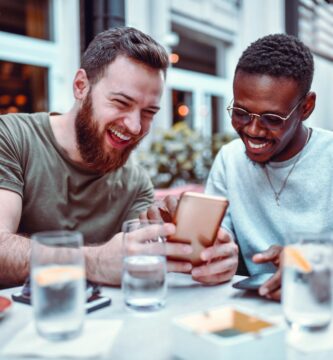 swedish male laughing while browsing social media with his african friend 1184006408 f206f254fbbf465183e0d72f183822c6