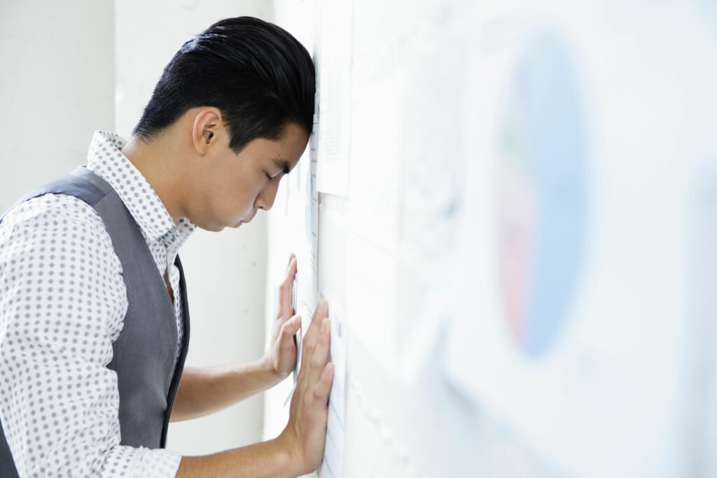 young man in office with head and hands against wall 176640285 5961b0d55f9b583f180cd3ac