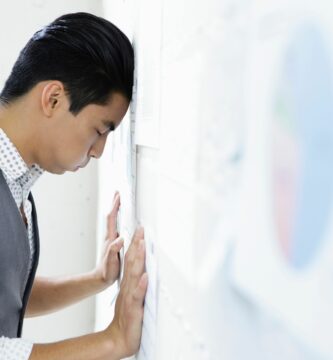 young man in office with head and hands against wall 176640285 5961b0d55f9b583f180cd3ac