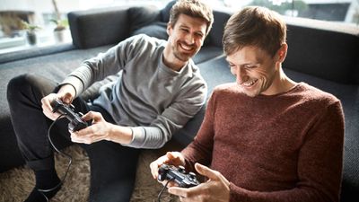 Dva muži hrající offline místní videohru pro více hráčů na své konzoli PlayStation 4.