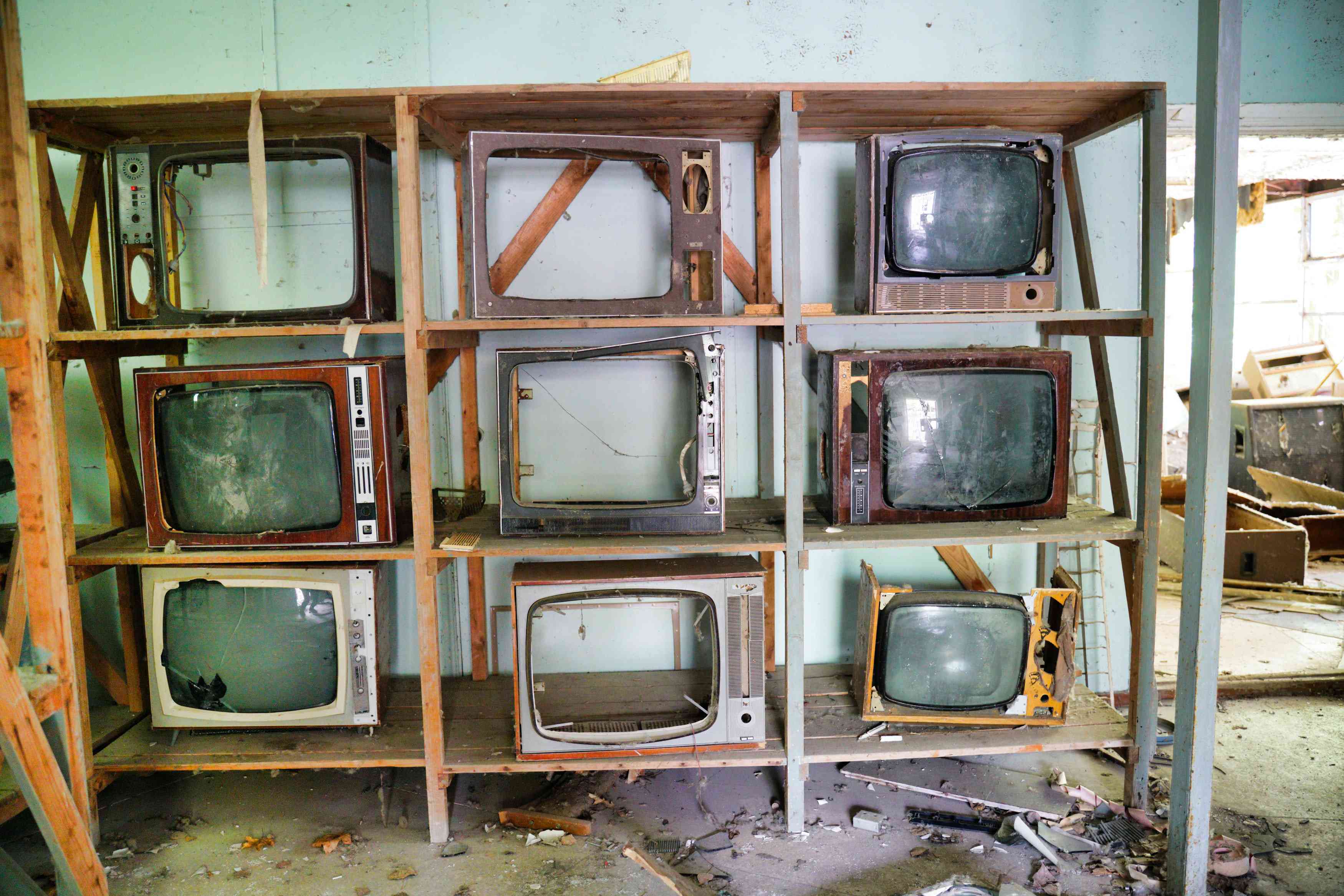 Rozbité retro televizory na polici v opuštěné budově. 