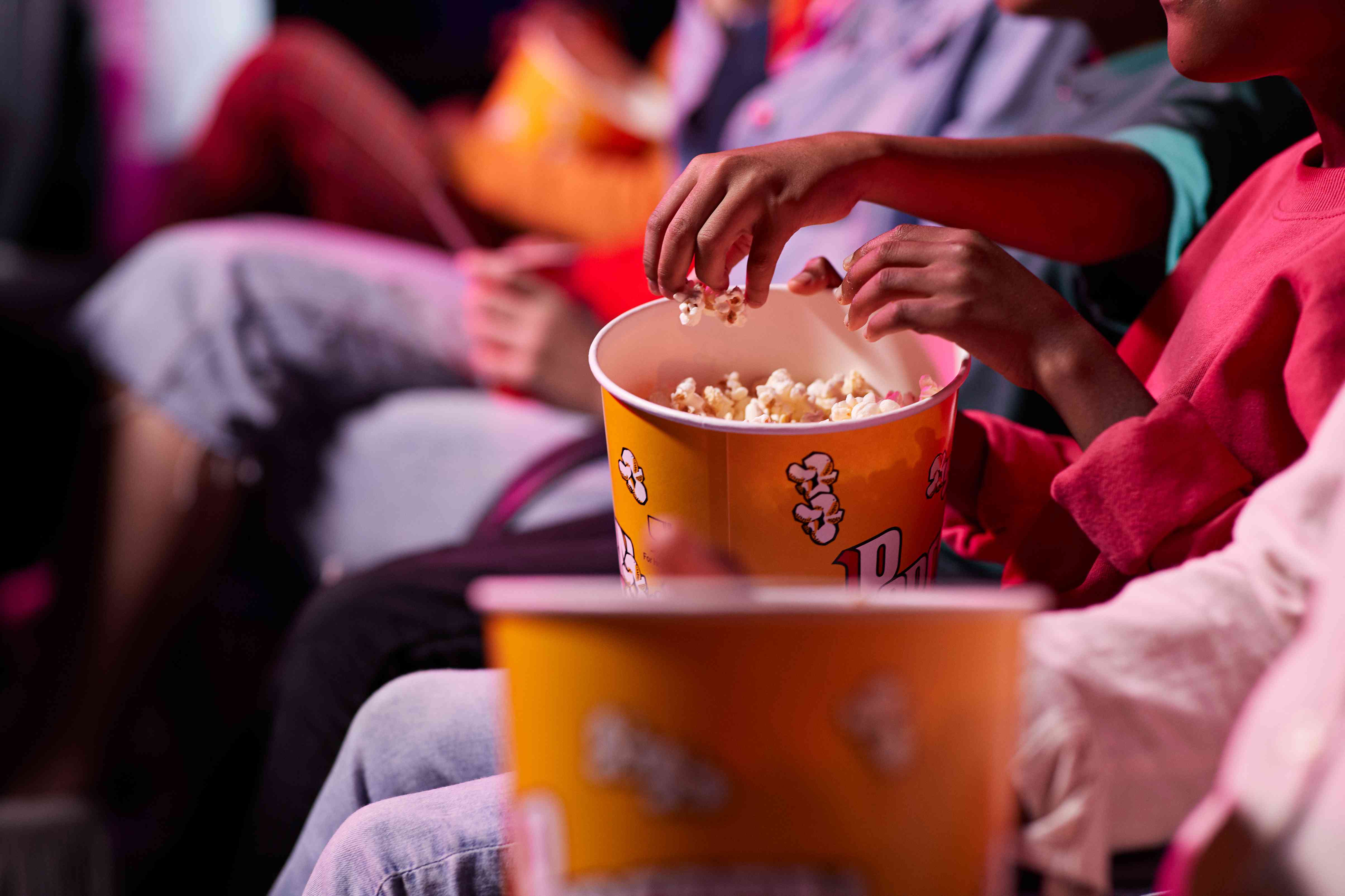 Bránice přátel, kteří sdílejí popcorn, zatímco sedí v divadle