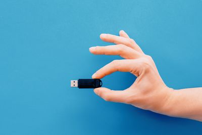 Ruka držící USB flash disk na modrém pozadí