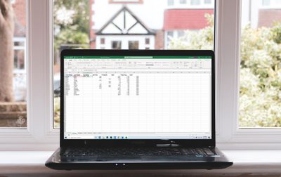 Notebook se systémem Windows sedící na okenním parapetu zobrazující Microsoft Excel.