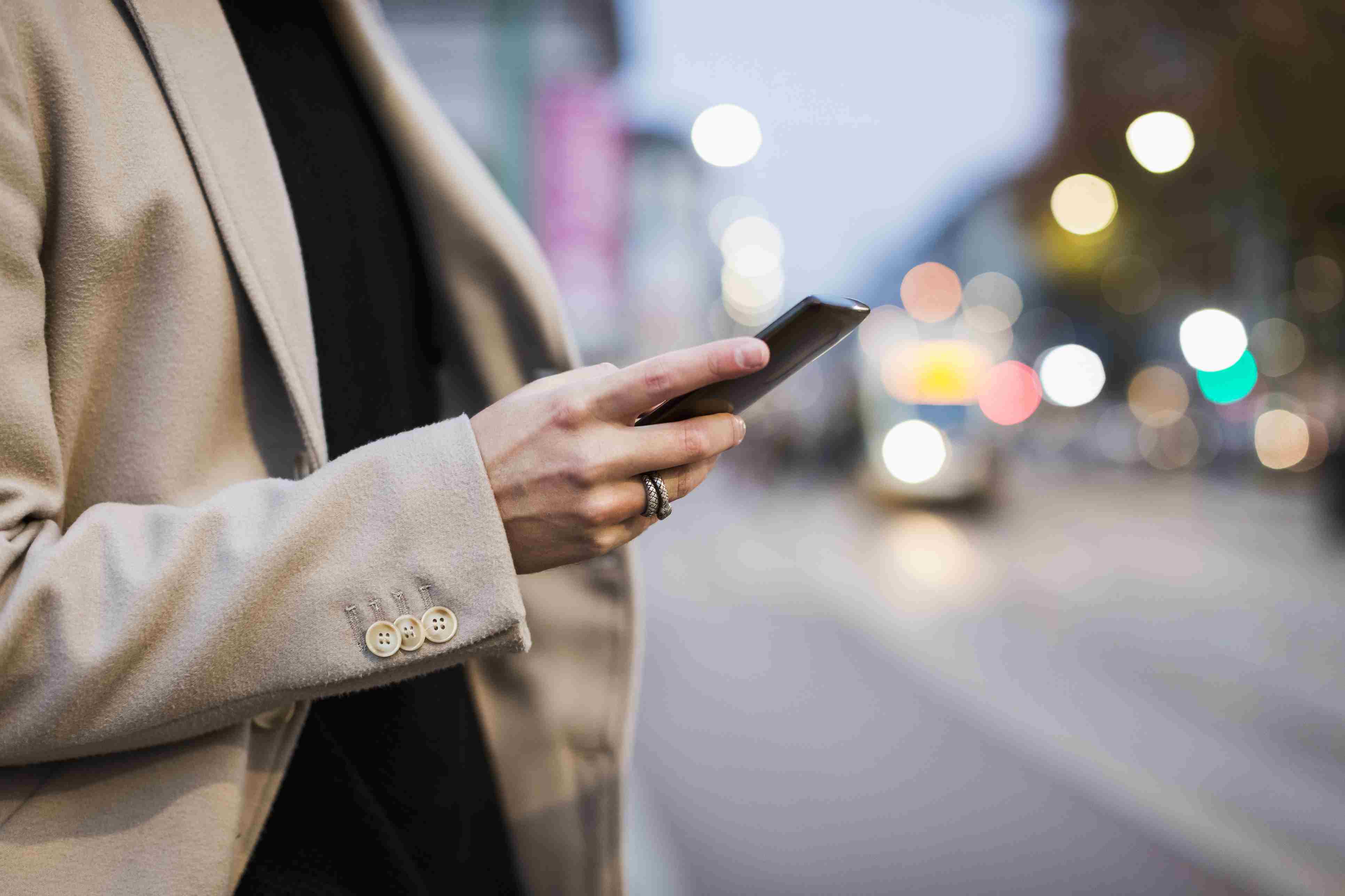 Detail člověka ve městě drží mobilní telefon