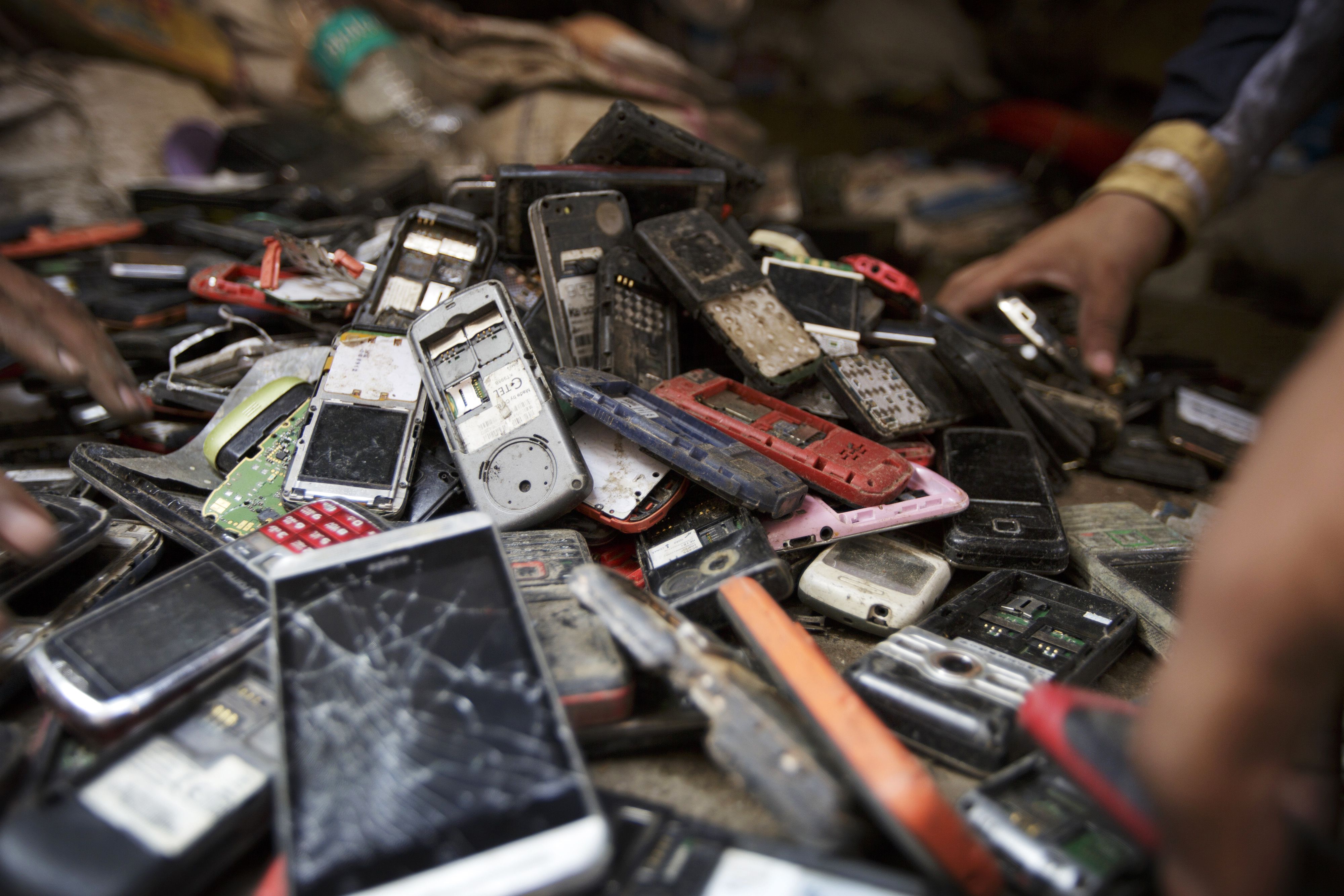 Pracovníci třídí hromadu použitých mobilních telefonů v indickém Dillí