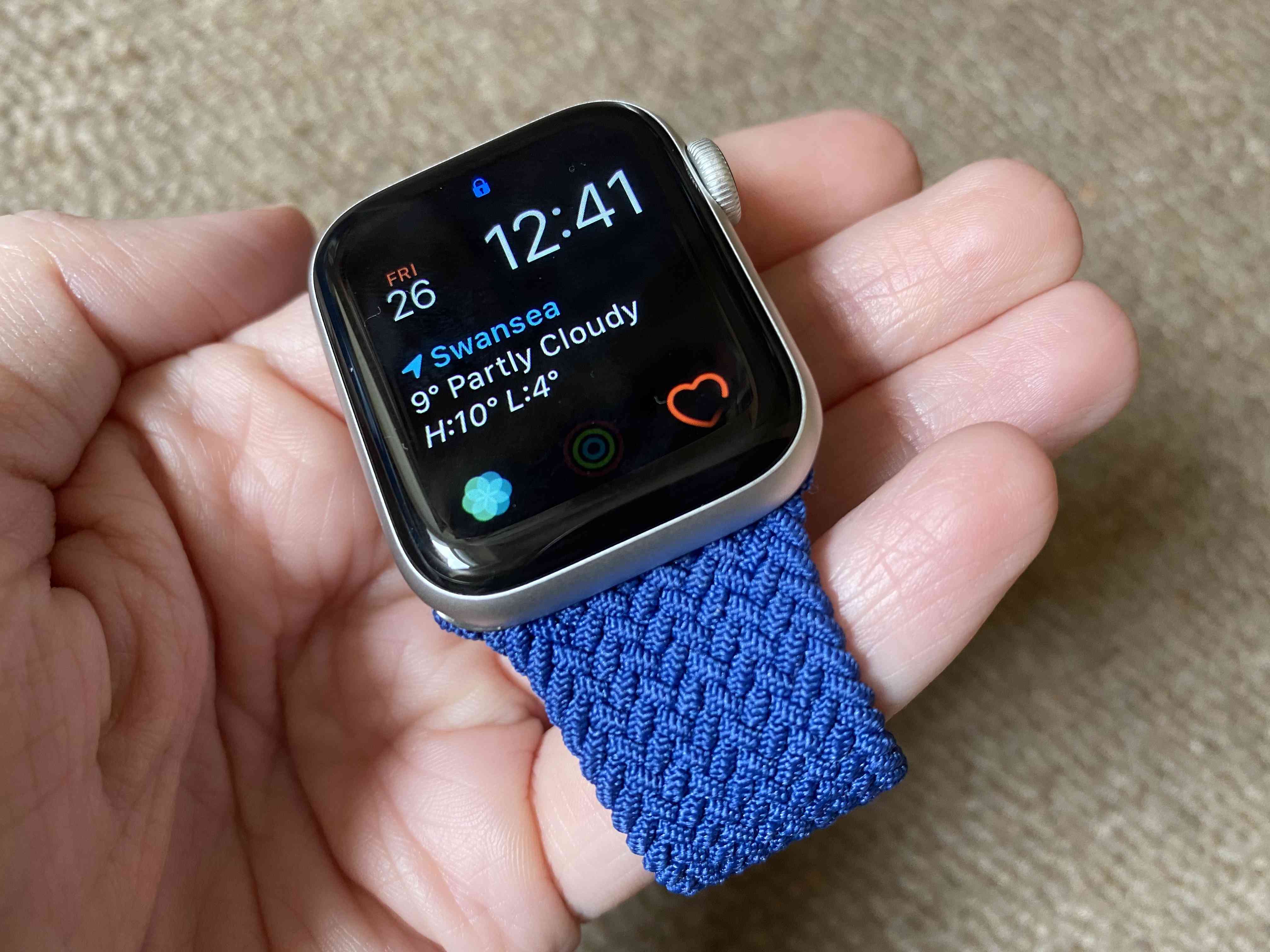 Apple hodinky s modrým pleteným sólovým poutkem drženým v něčí ruce