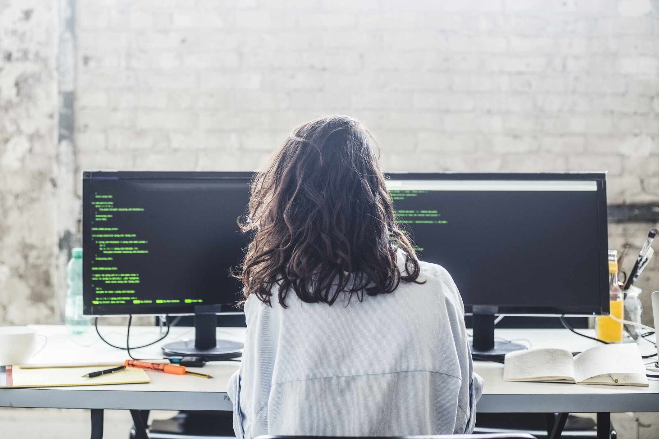 Zadní pohled na ženské počítačový hacker kódování u stolu v kreativní kanceláři