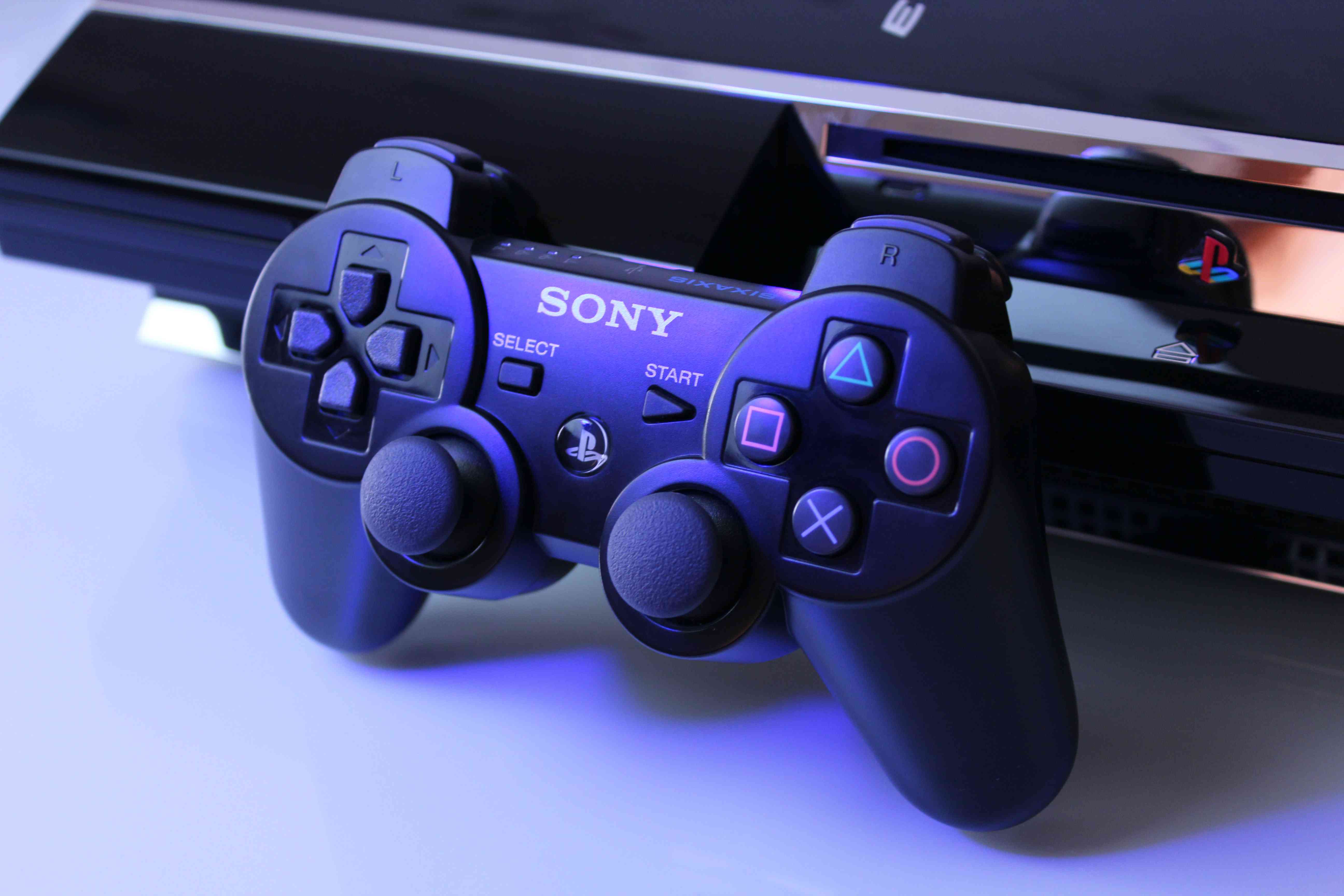 Detailní záběr na PlayStation 3 s ovladačem. 
